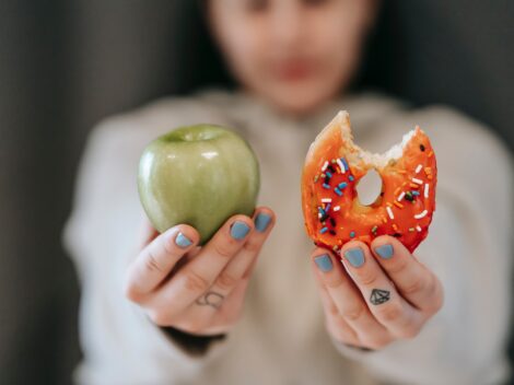 woman-showing-apple-and-bitten-doughnut